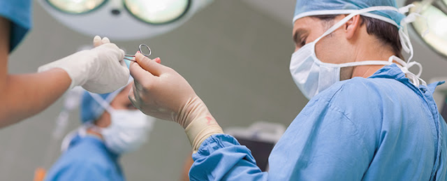 Doctor receiving a surgical scissor from a nurse in operating theater