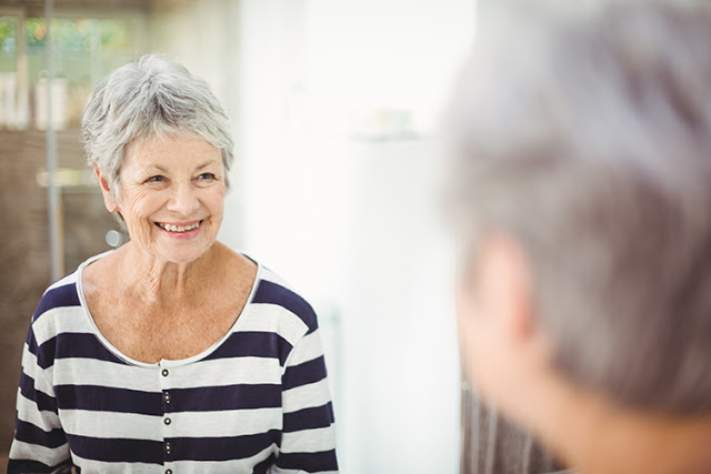 Reflection of happy senior woman on mirror in bathroom